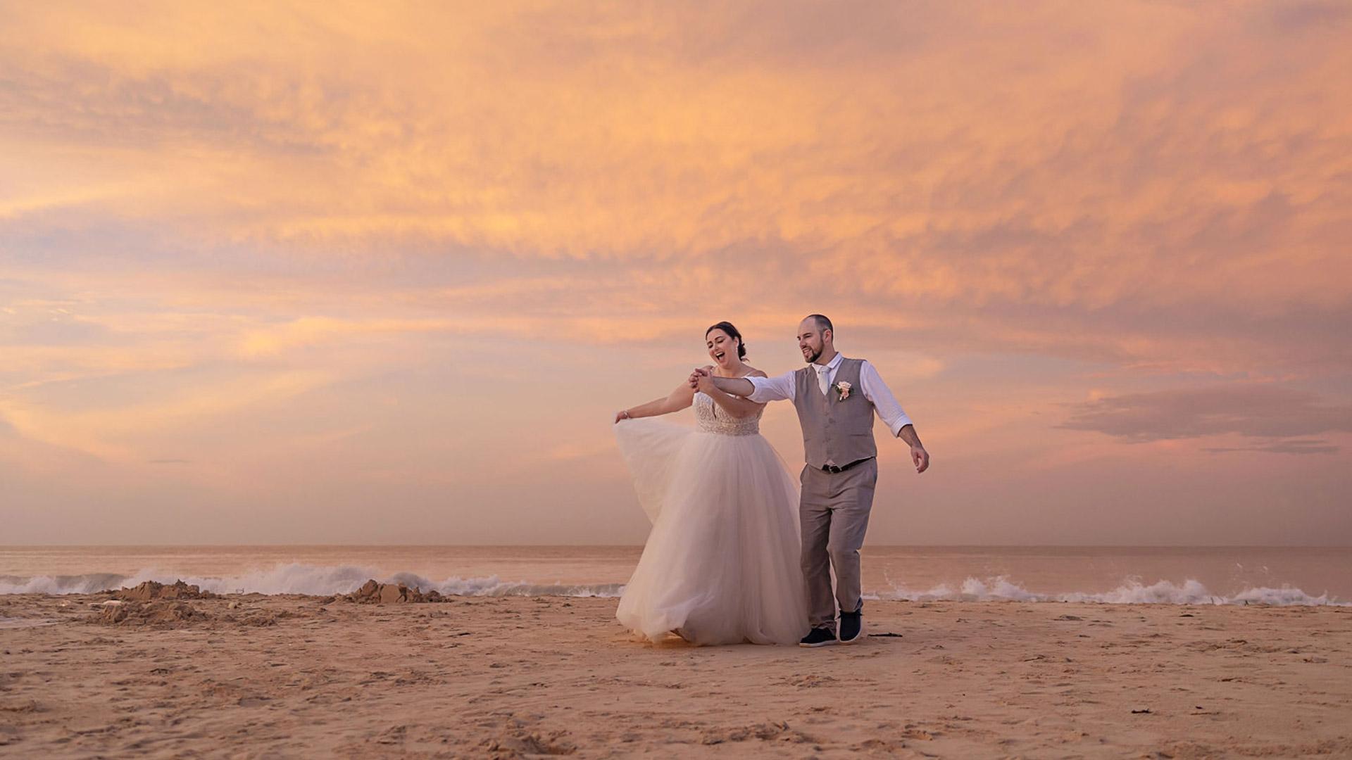 Bride and groom on a beach at sunset.