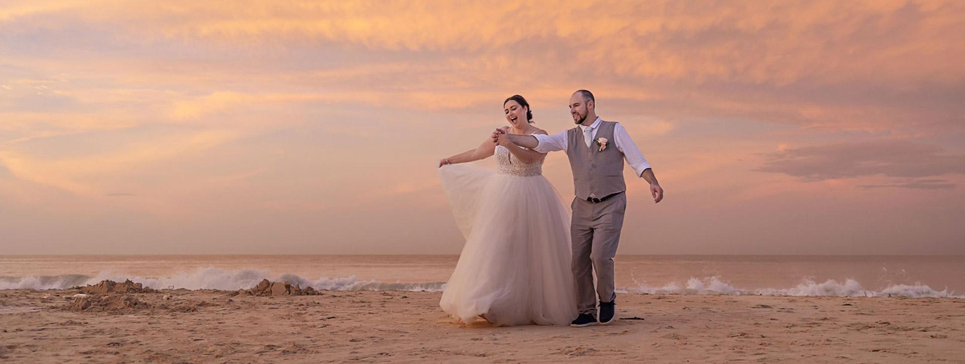 Bride and groom on a beach at sunset.