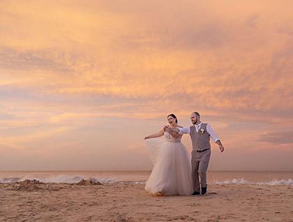 Bride and groom on a beach at sunset.