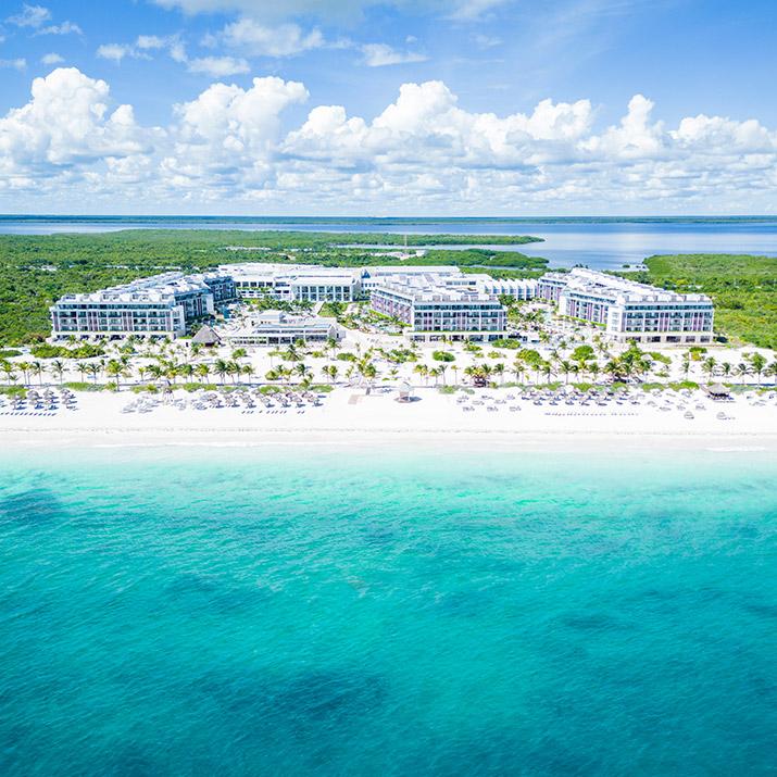 An expansive aerial view highlights the extensive beachfront, luxurious buildings, and turquoise waters surrounding Majestic Elegance Costa Mujeres.