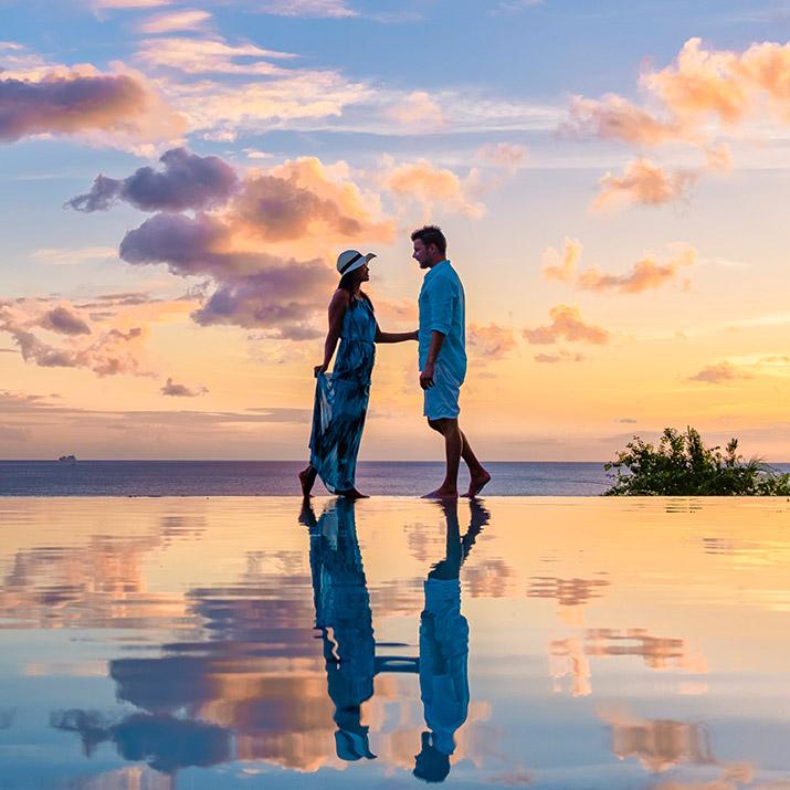 Couple standing on the beach at sunset