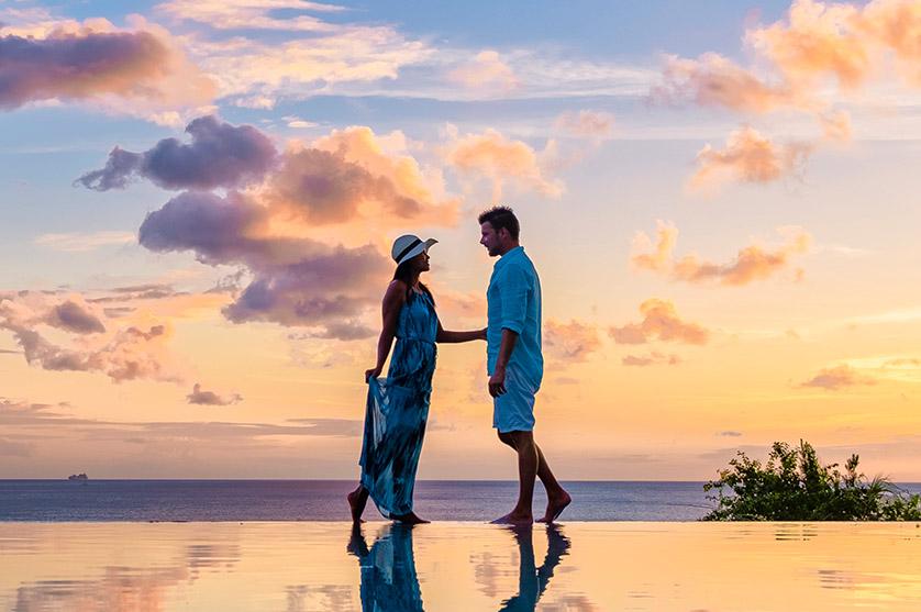 Couple standing in front of the ocean at sunset