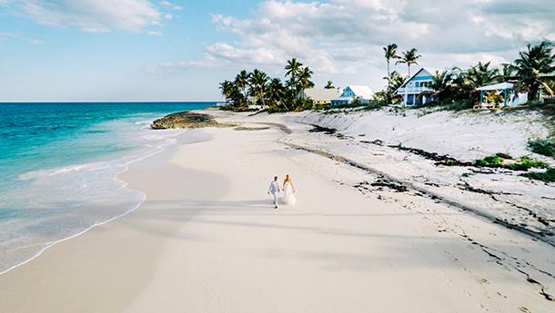 A newlywed couple walk along a beach