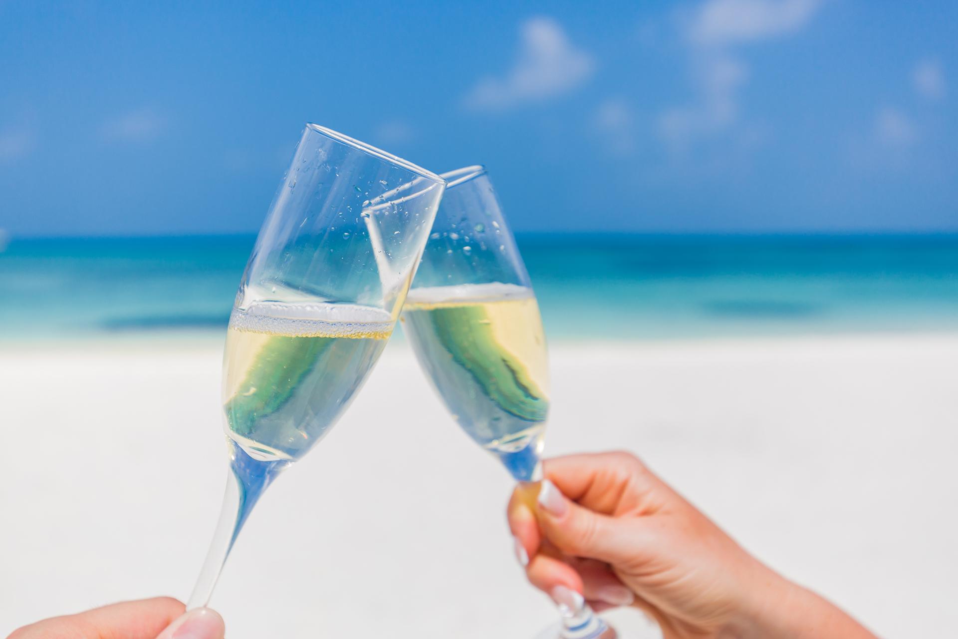 Couple clicking champagne glasses on the beach