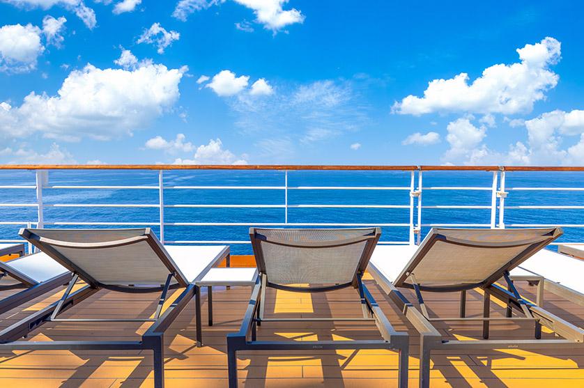 Lounge chairs on a cruise deck overlooking the open sea during the day