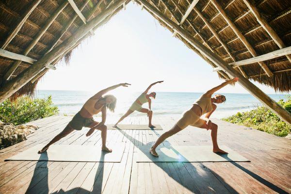 3 woman doing yoga near a beach
